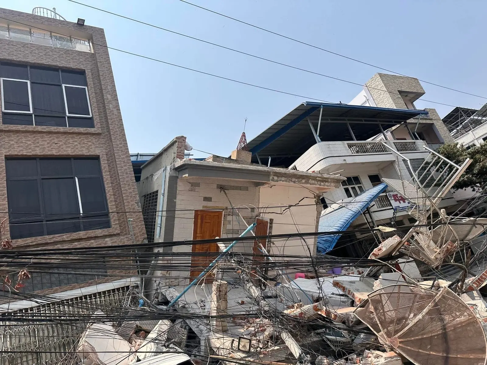 A house collapsed onto the street beneath fallen power lines in Mandalay