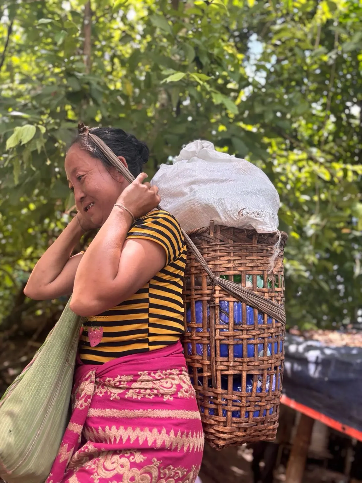 A woman carries relief supplies home in a woven basket on her back in Karenni