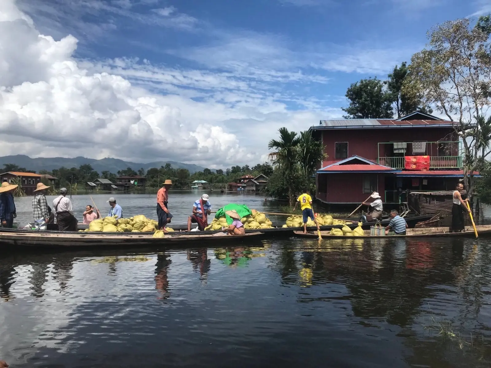 Two long boats loaded with relief sacks are poled between flooded stilt houses