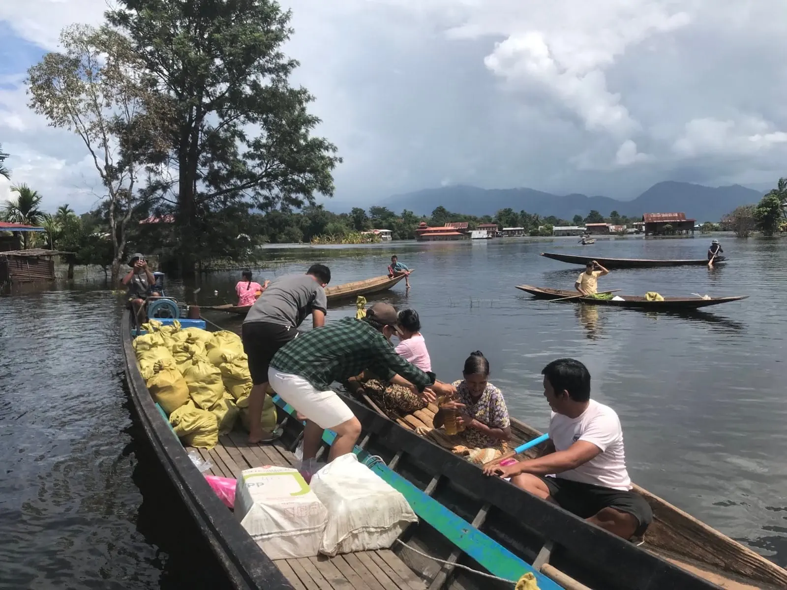 A relief team hands supplies to an elderly woman from a boat stacked with food sacks