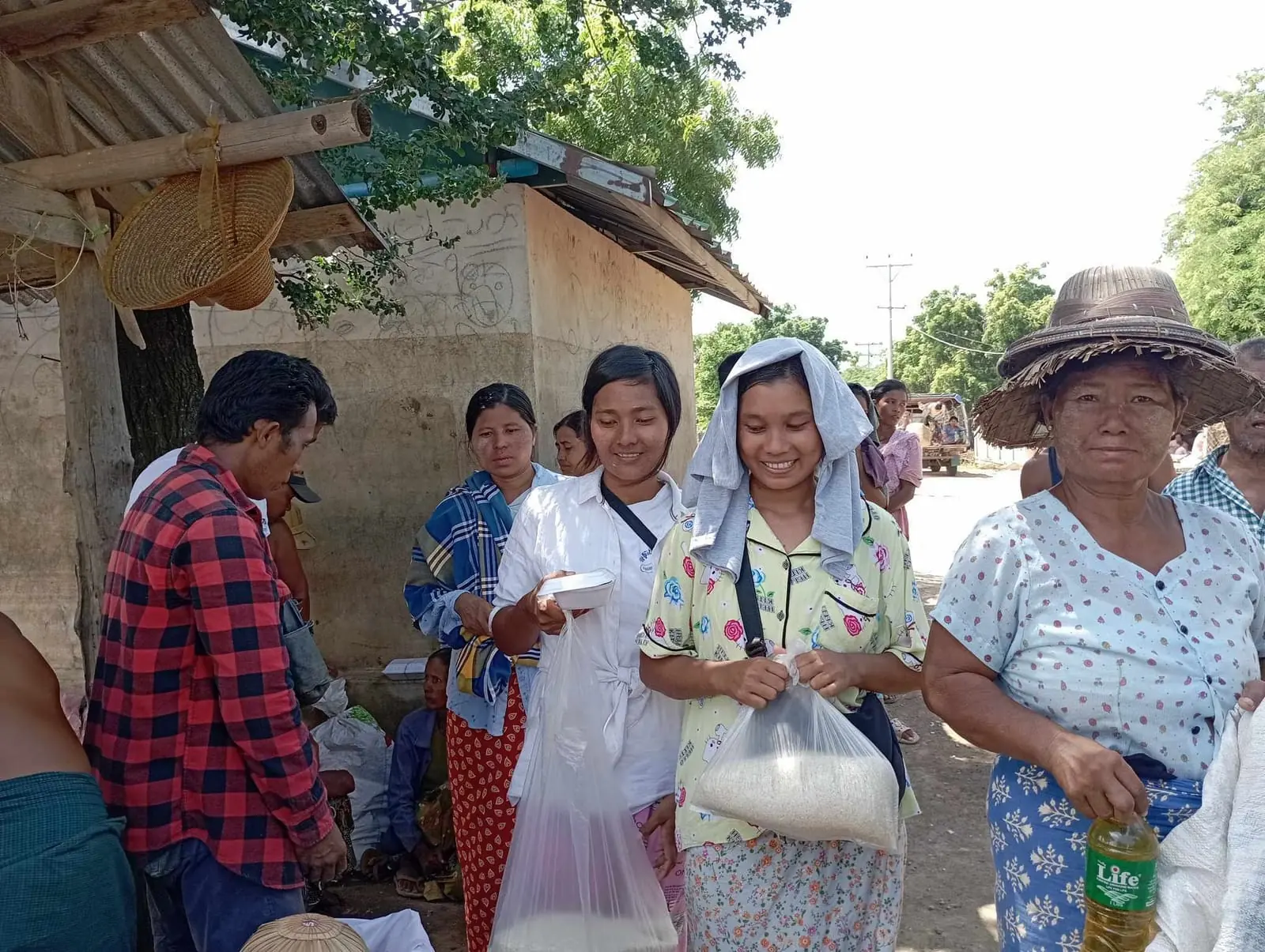 Women receive bags of rice and bottles of cooking oil at a village distribution in Mandalay
